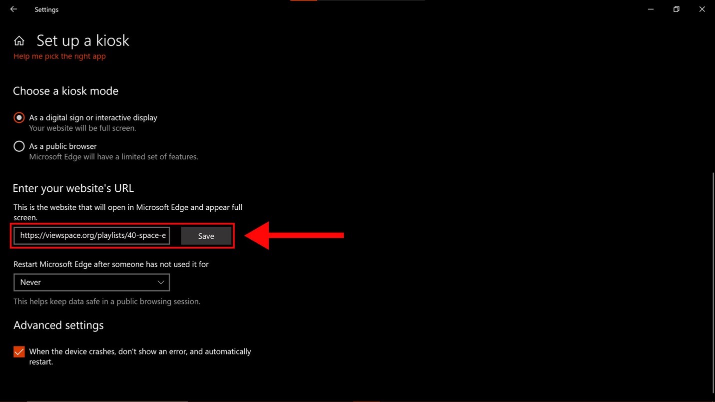 Screenshot of the “Set up a kiosk” window as seen on a Windows computer. Just below is the “Choose a kiosk mode” section, which lists two options. The first option, “As a digital sign or interactive display,” is selected. Further below is the “Enter your website’s URL” section, which has two text entry boxes. A large red arrow points to the first box, which is also highlighted by a red rectangle. A ViewSpace URL is entered in the field. Just below is a second box, which has “Never” selected. At the bottom of the screen, beneath “Advanced settings" the "When the device crashes, don't show an error, and automatically restart" checkbox is selected.