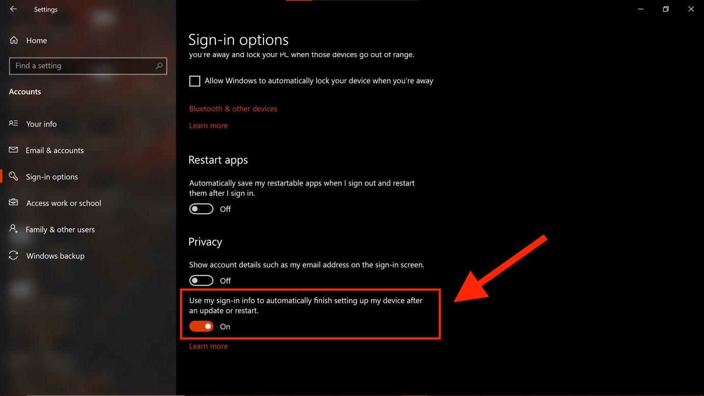 Screenshot of the “Sign-in options” window as seen on a Windows computer. Toward the bottom, underneath the “Privacy” section, there are two buttons. A large red arrow points to the second button, which is also highlighted by a red rectangle. The second button is labeled "Use my sign-in info to automatically finish setting up my device after an update or restart." The button is toggled on.